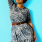 Woman wearing a leopard print breastfeeding dress against a blue background