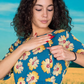 Woman wearing a blue floral dress against a bright blue sky. Showing zip breastfeeding dress access.