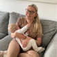 Woman holding a baby on a couch with a colorful abstract painting in the background in her mocha cotton breastfeeding pyjajams