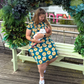 Woman in the a sunflower breastfeeding dress breastfeeding her baby showing the easy access zips for breastfeeding. 